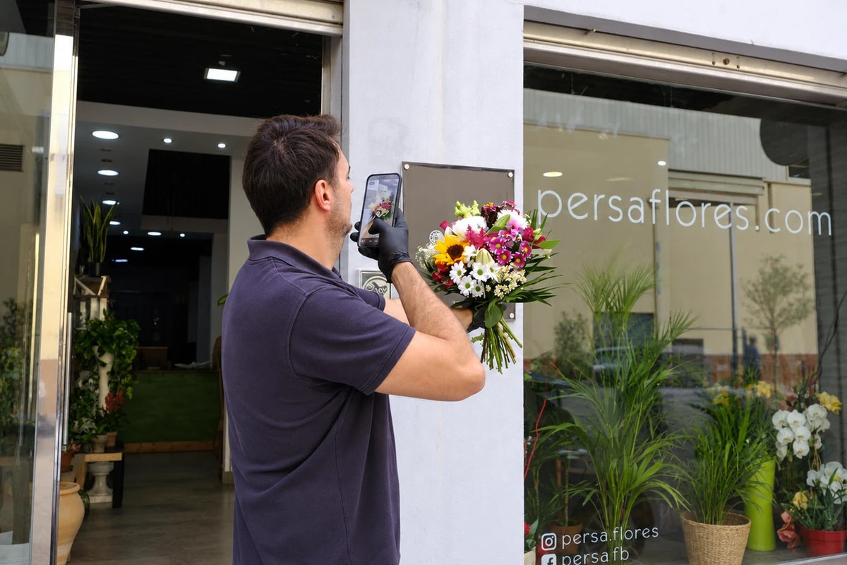 José Antonio photographing a bouquet in front of the Persa Flores shop window before it leaves