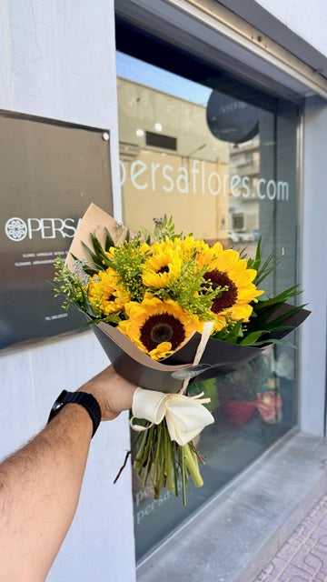 The wrapped Helios Bouquet with a light bow, held outside Persa Flores before dispatch.